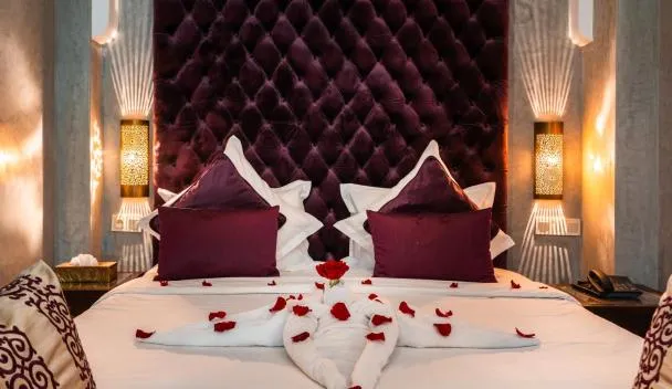 Chambre romantique préparée avec pétales de roses dans un riad marocain, réservée par un couple